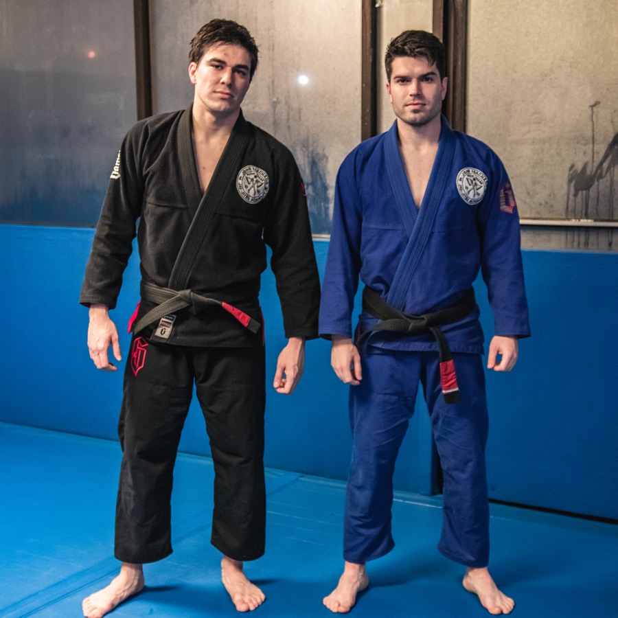 John, in a blue gi, standing with his brother, Jean, in a black gi, both wearing black belts